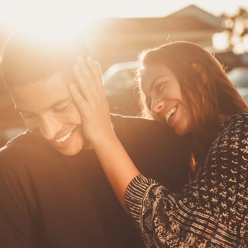 a woman is putting her hand on a man 's ear .