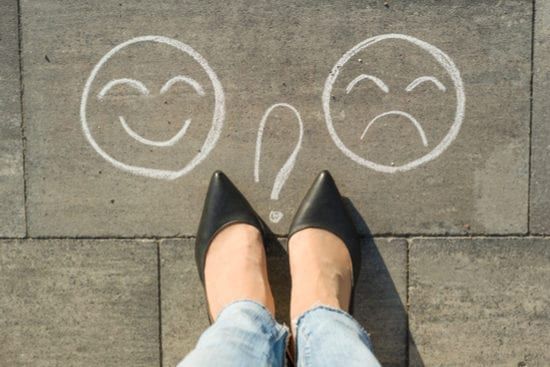 a woman is standing on a sidewalk with a smiley face and a question mark drawn on the ground .
