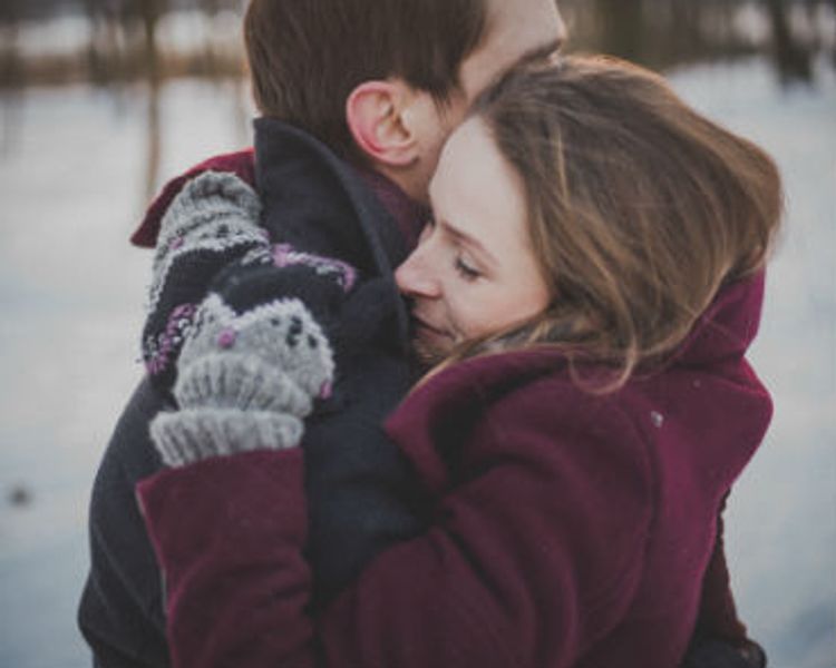a man and a woman are hugging each other in the snow .