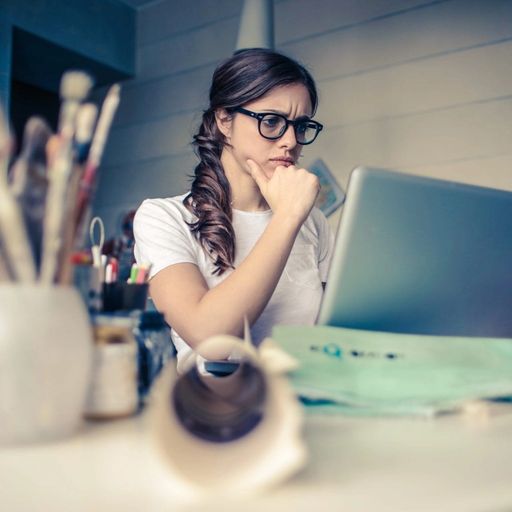 a woman is sitting at a desk using a laptop computer .