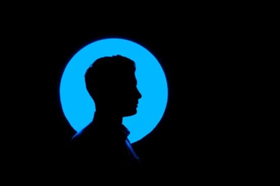 a silhouette of a man 's head in a blue circle on a black background .