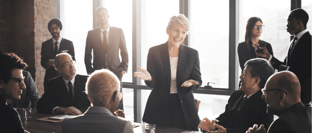 a woman is giving a presentation to a group of business people