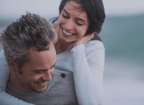 a man is carrying a woman on his back and they are smiling