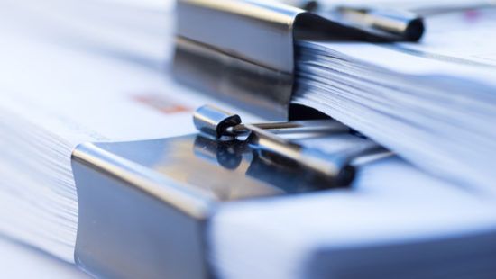a close up of a stack of binder clips on top of a stack of papers .