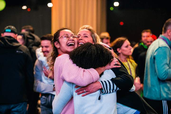 a woman in a pink sweater is hugging another woman