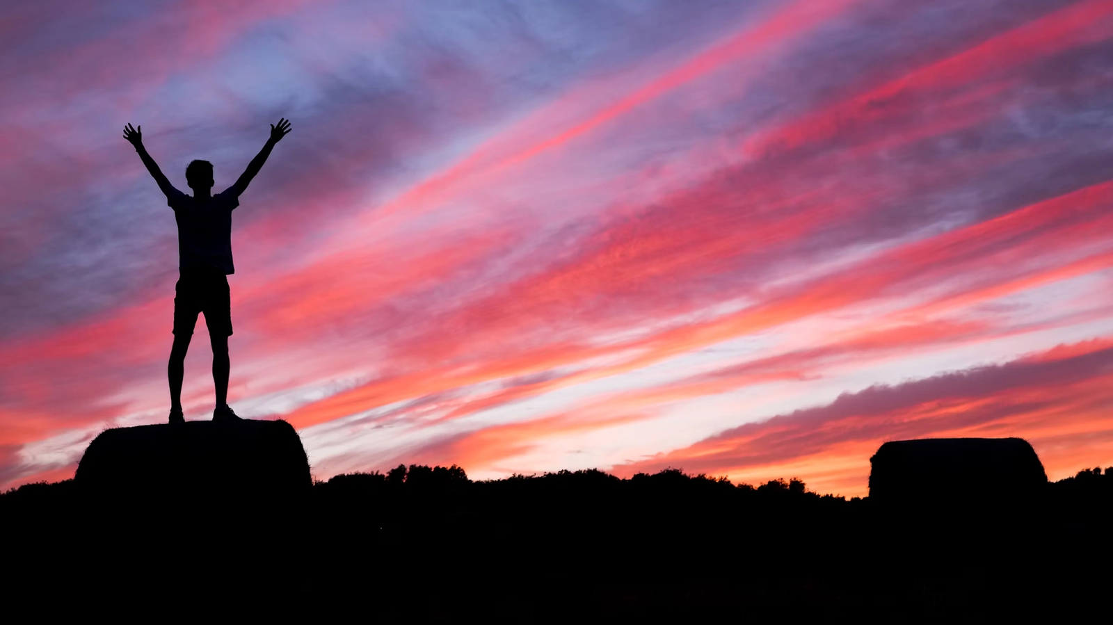 a man stands on top of a rock with his arms in the air