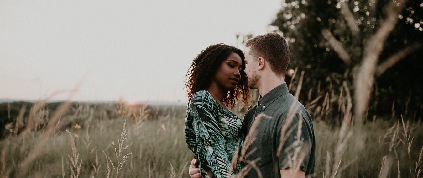 a man and a woman are standing in a field looking at each other .