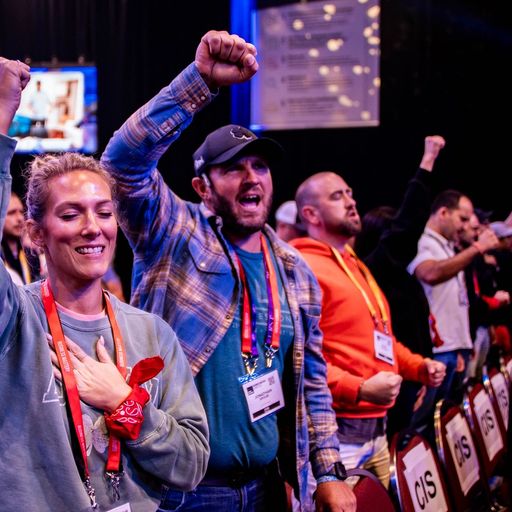a group of people are standing in a room with their hands in the air .