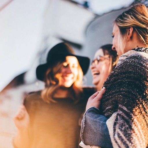 a group of women are standing next to each other and laughing .