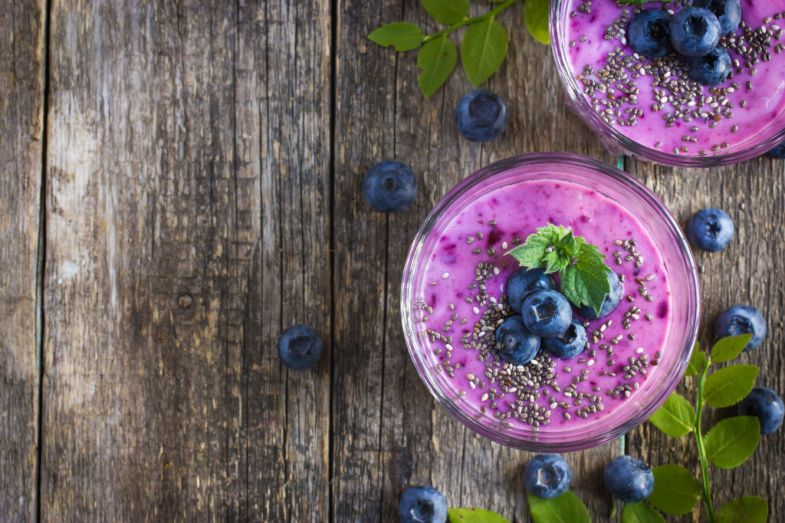 two bowls of blueberry smoothie with chia seeds and blueberries on a wooden table .
