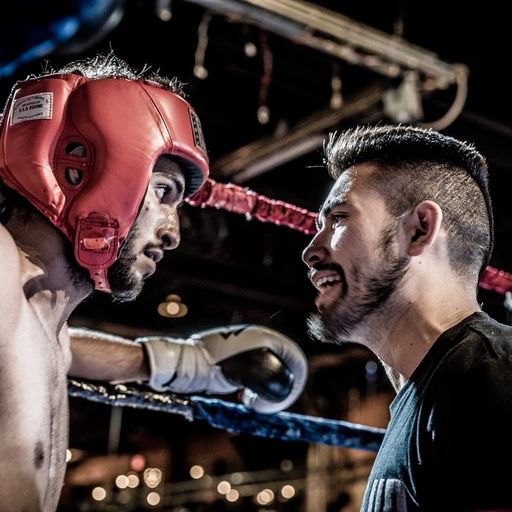 two men are standing in a boxing ring looking at each other .