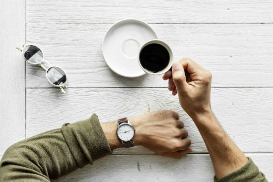a man is sitting at a table drinking a cup of coffee .