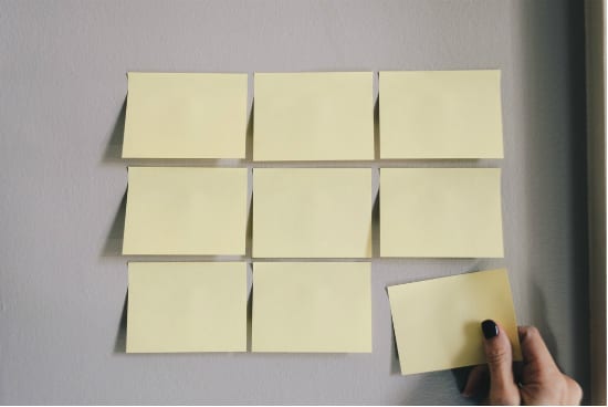 a person is holding a piece of paper next to a bunch of sticky notes on a wall .