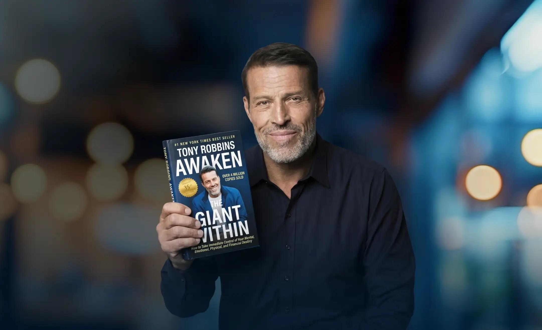 Tony Robbins holding his book "Awaken the Giant Within".
