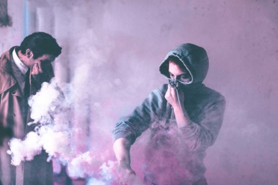 two men are standing in a room with smoke coming out of their mouths .