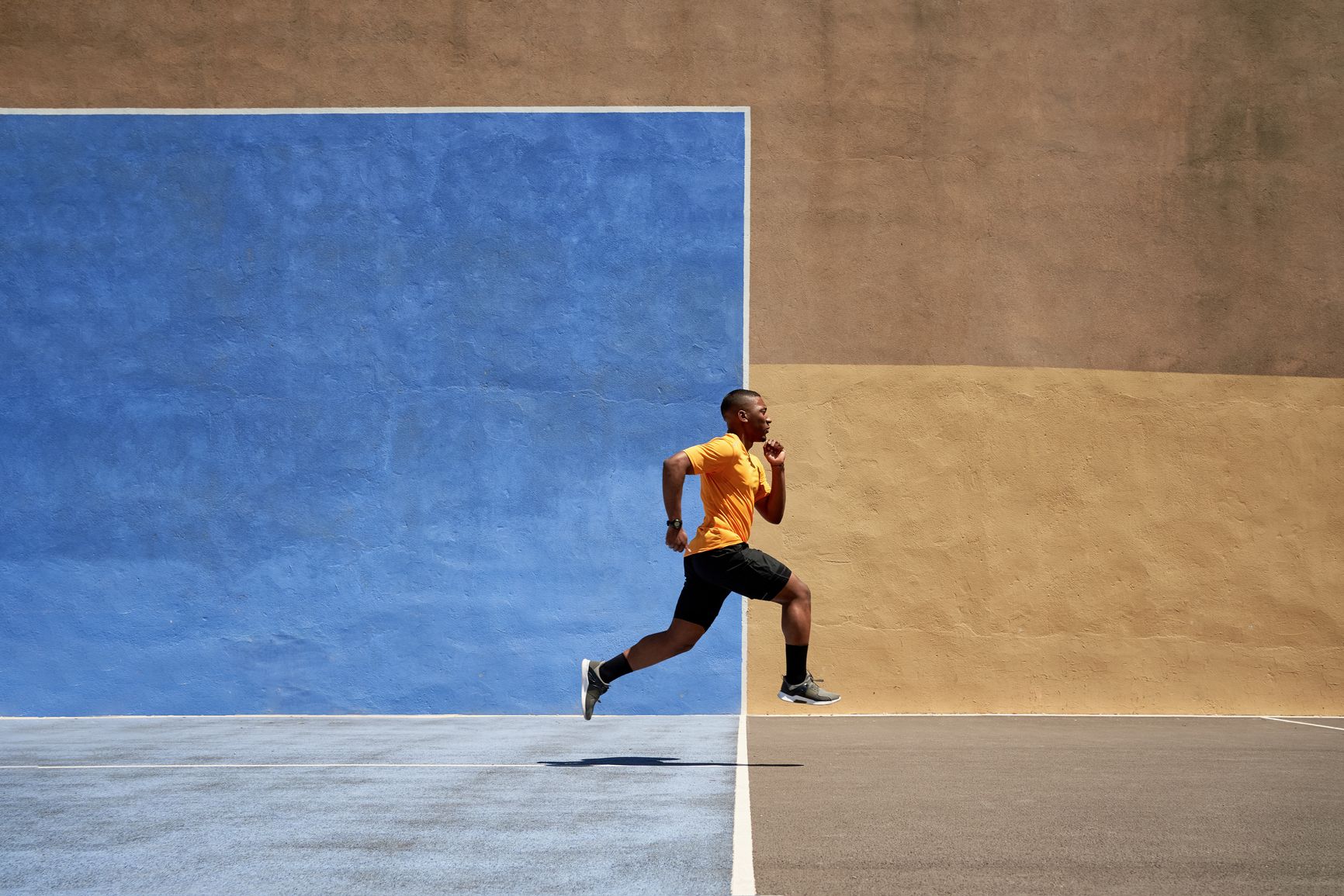 a man in a yellow shirt and black shorts is running on a basketball court .