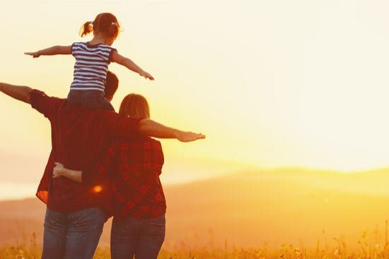 a man and woman are carrying a little girl on their shoulders .