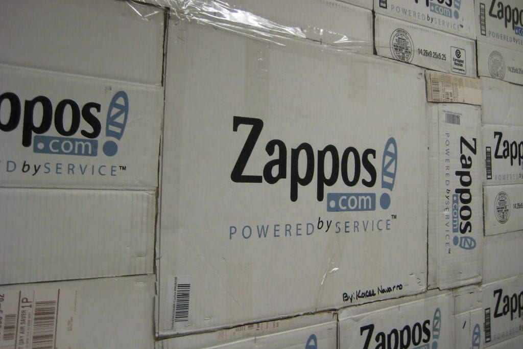 a wall of zappos boxes stacked on top of each other .