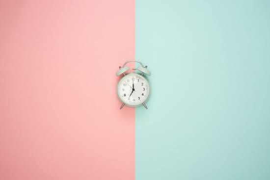 an alarm clock is sitting on a pink and blue background .