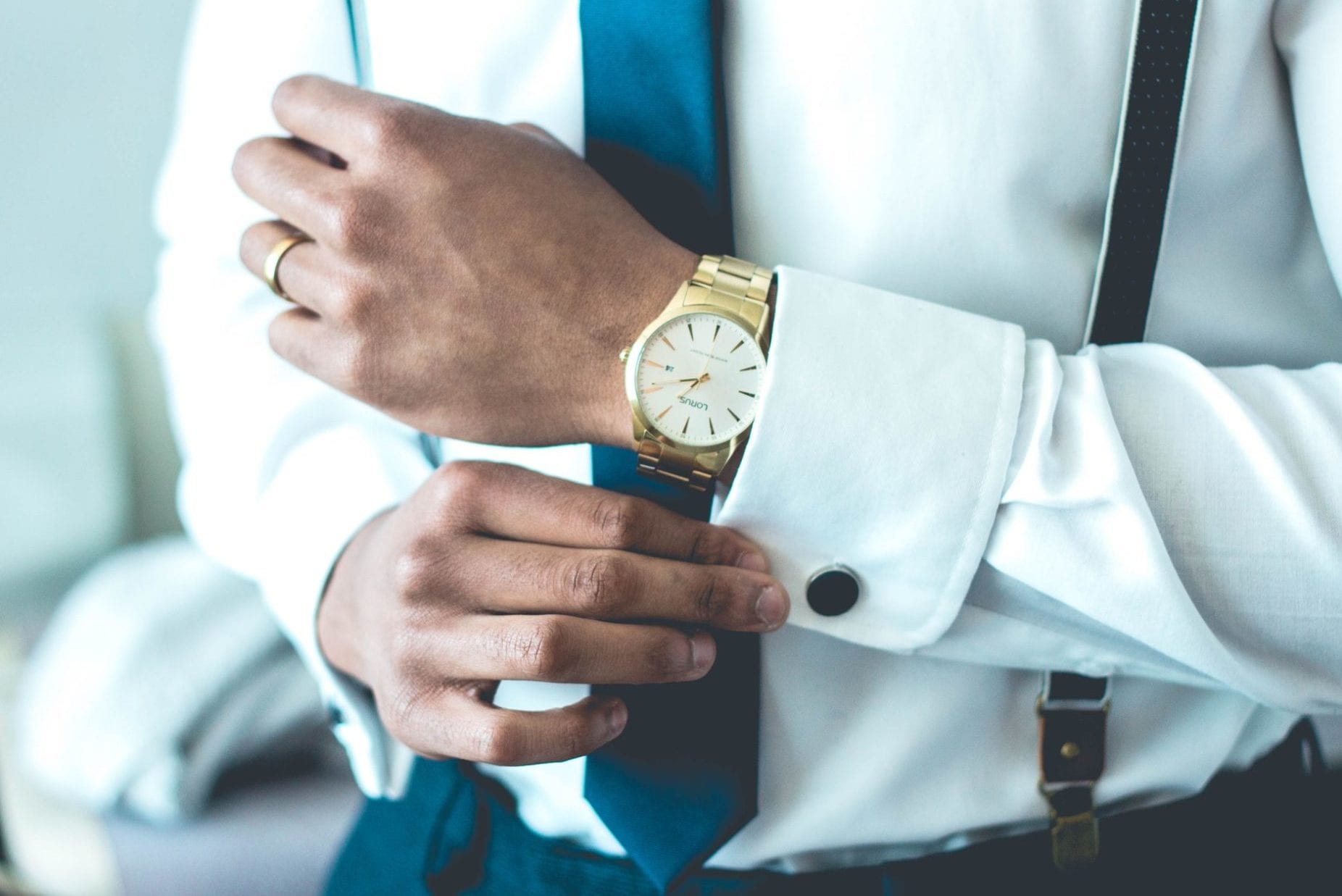a man in a suit and tie is adjusting his watch .