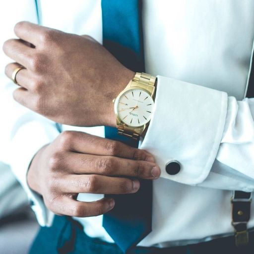 a man in a suit and tie is adjusting his watch .