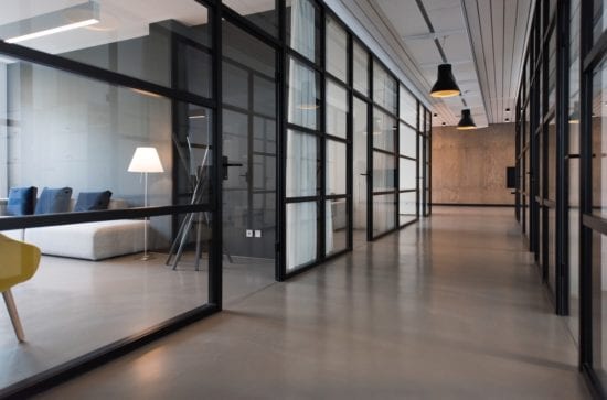 a long hallway with glass walls and a living room in the background .