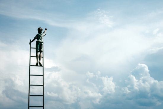 a man is standing on top of a ladder against a cloudy sky .