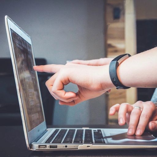 two people are pointing at a laptop computer screen .