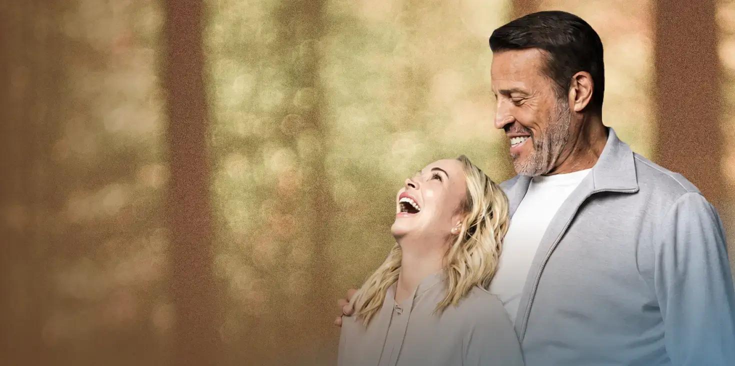 Tony Robbins smiles down at Sage Robbins, who is laughing joyfully.