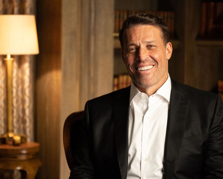 a man in a suit and white shirt is sitting in a chair and smiling .