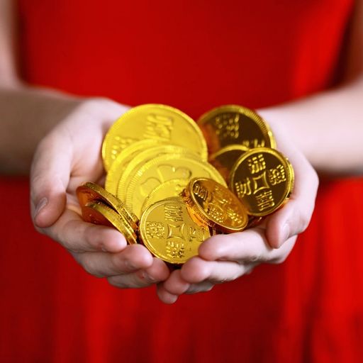 a woman in a red dress is holding a pile of gold coins in her hands .