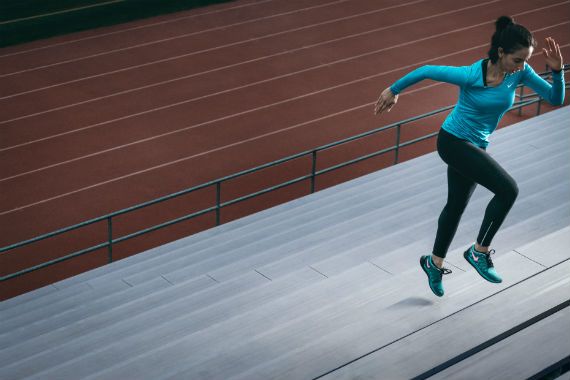 a woman is jumping in the air while running on a track .