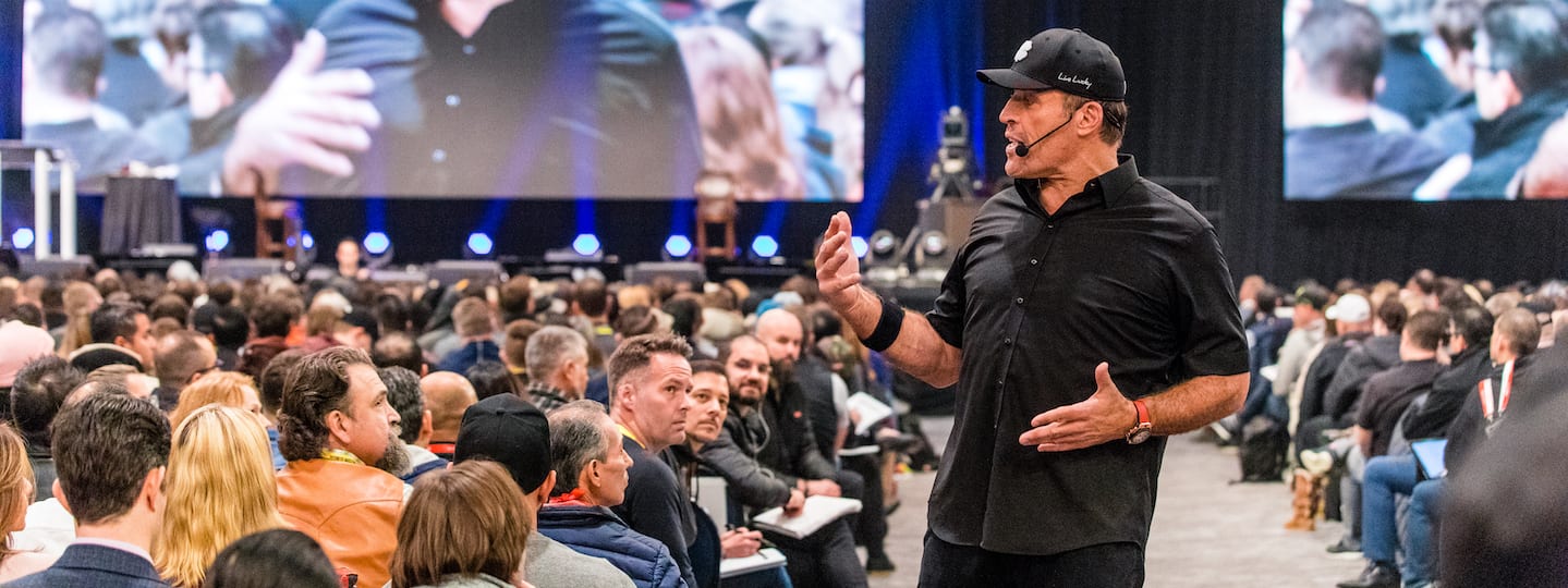 a man is standing in front of a crowd of people giving a presentation .