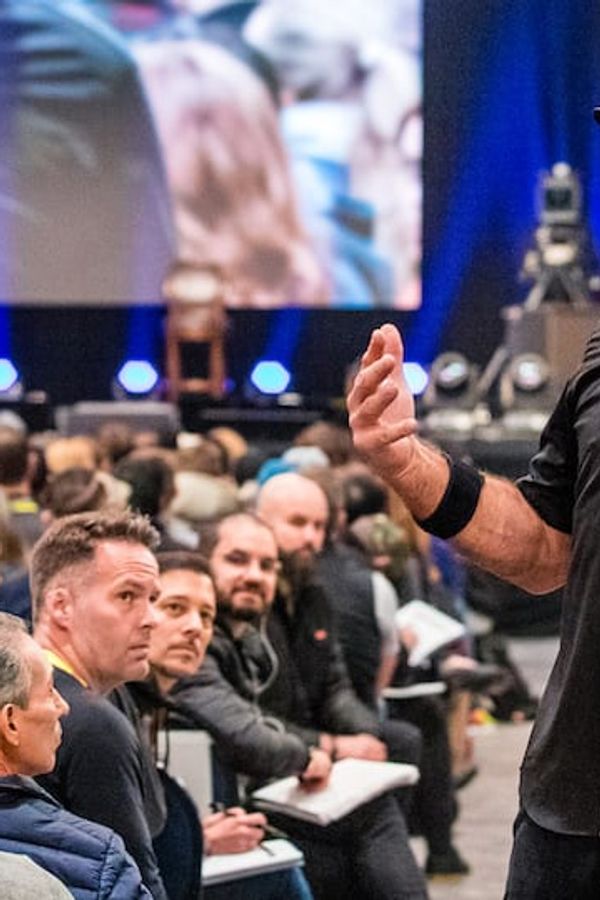 a man is standing in front of a crowd of people giving a presentation .