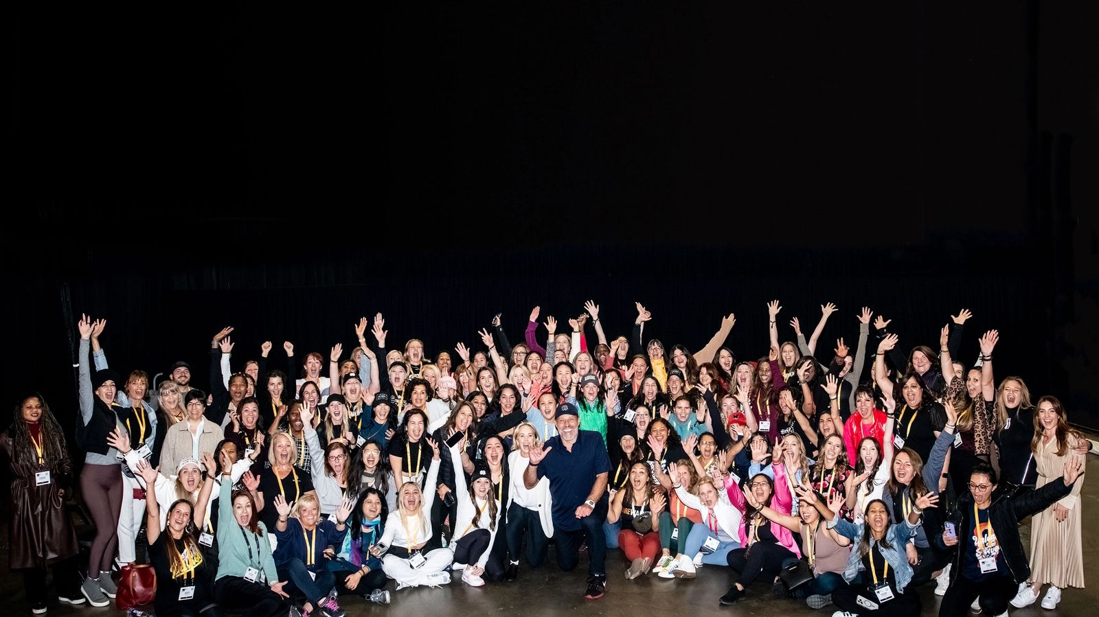 a large group of people are posing for a picture in front of a black background .