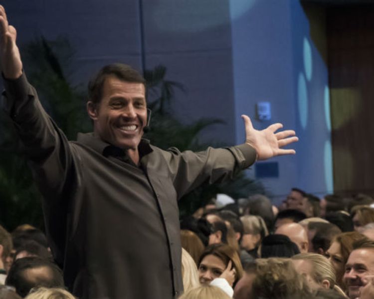 a man is standing in front of a crowd with his arms outstretched