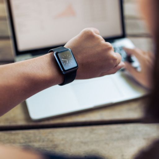 a woman is wearing a smart watch while using a laptop computer .