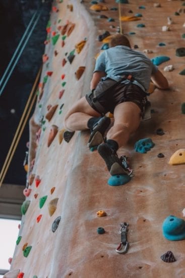 a man is climbing up a climbing wall in a gym .