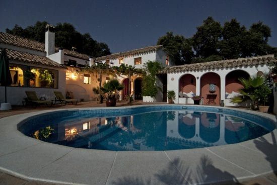 a large swimming pool in front of a house at night .