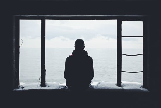 a man is looking out of a window at the ocean .