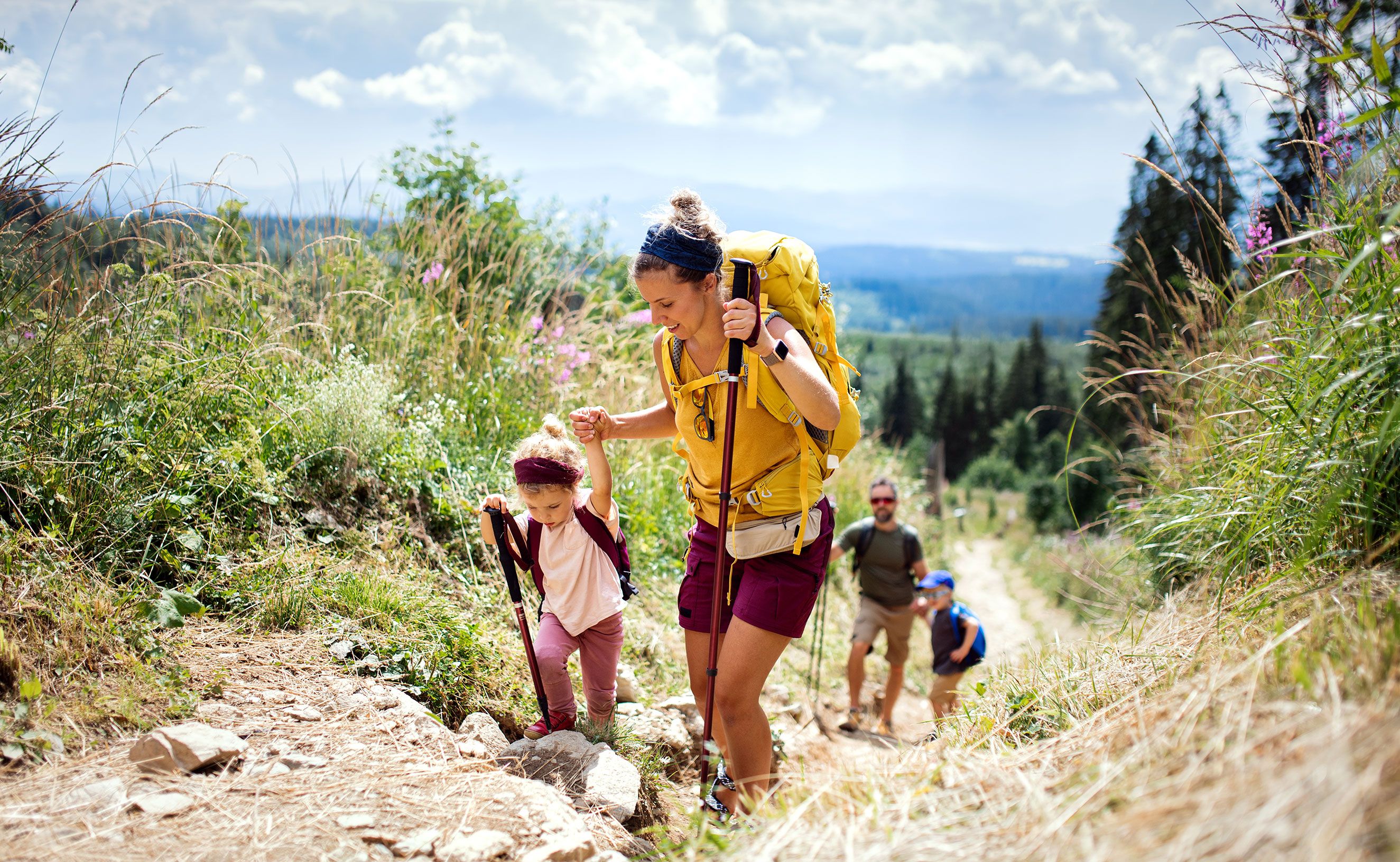 a woman and two children are hiking up a hill .