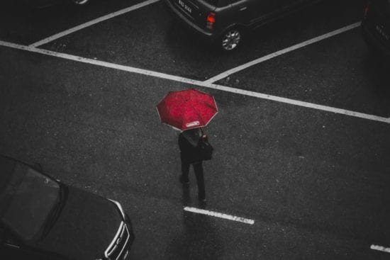 a person is holding a red umbrella in the rain .