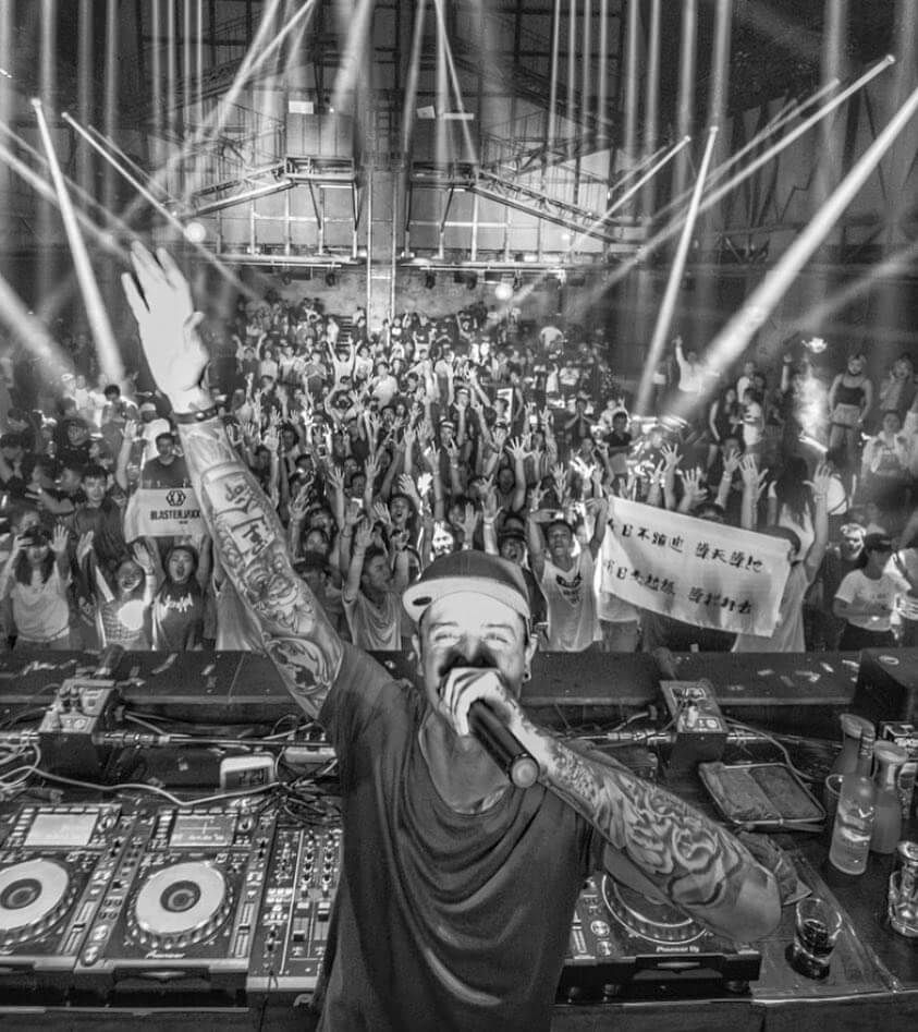 a dj stands in front of a crowd with a sign that says ' boys ' on it