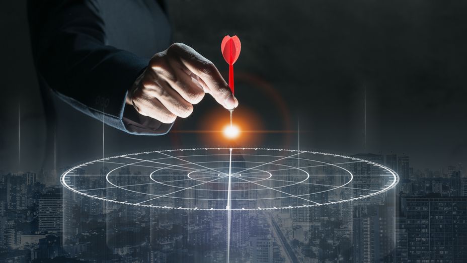 a person is holding a dart in front of a target .