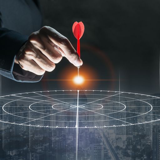a person is holding a dart in front of a target .