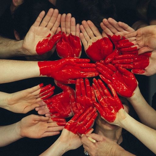 a group of people are making a heart with their hands painted red .
