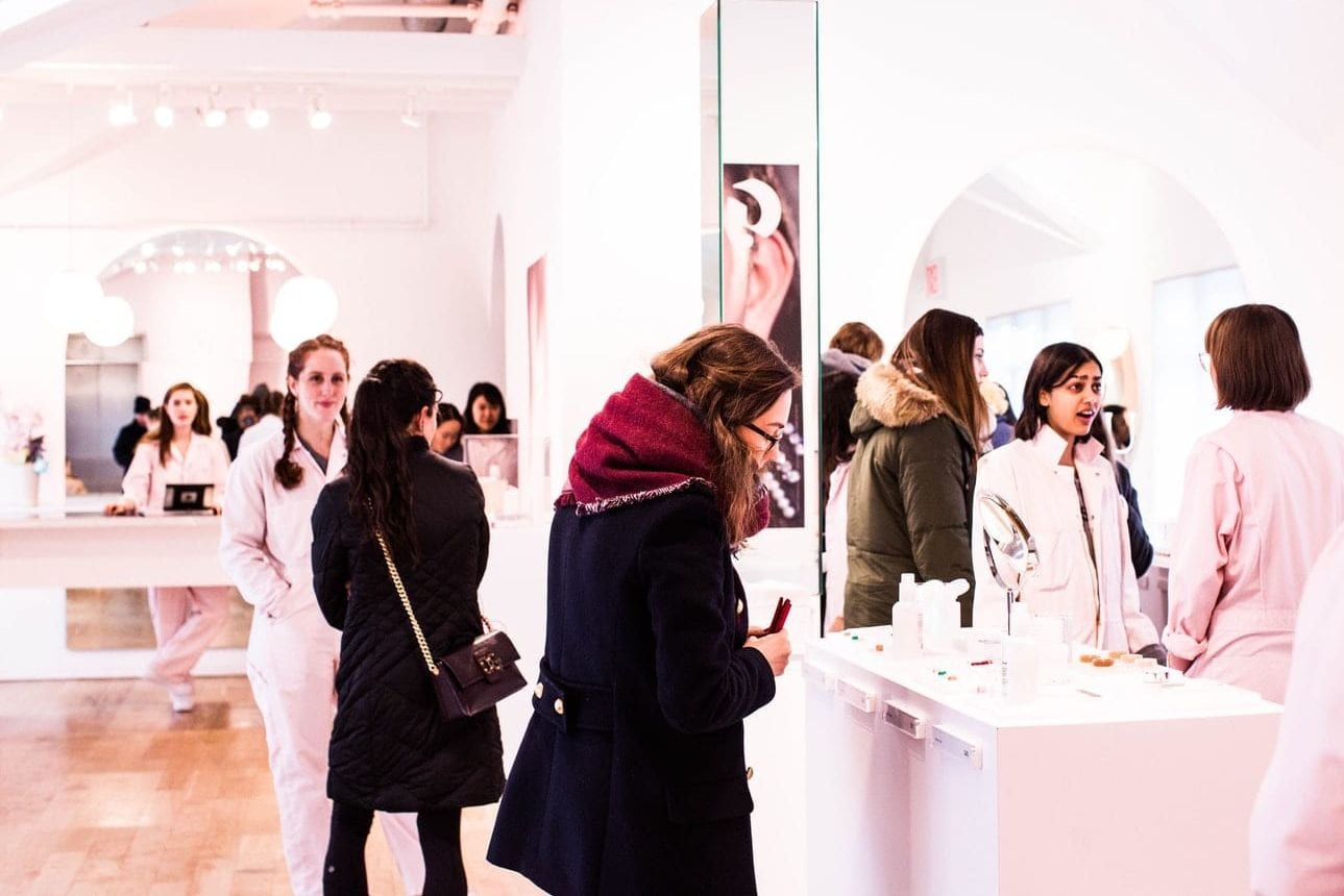 a group of women are standing in a store looking at their phones .