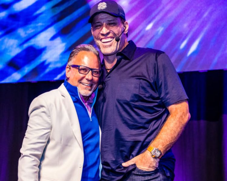 two men are standing next to each other on a stage and smiling .