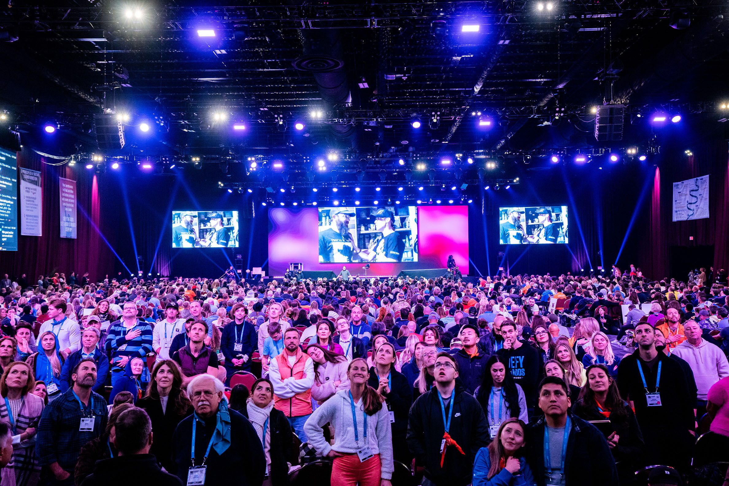 a large group of people are standing in front of a stage at a conference .