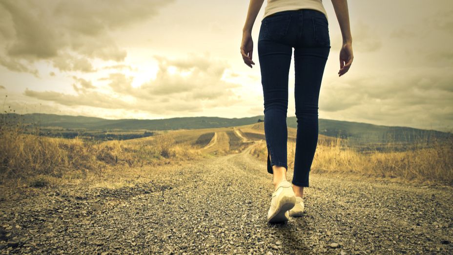 a woman is walking down a dirt road .